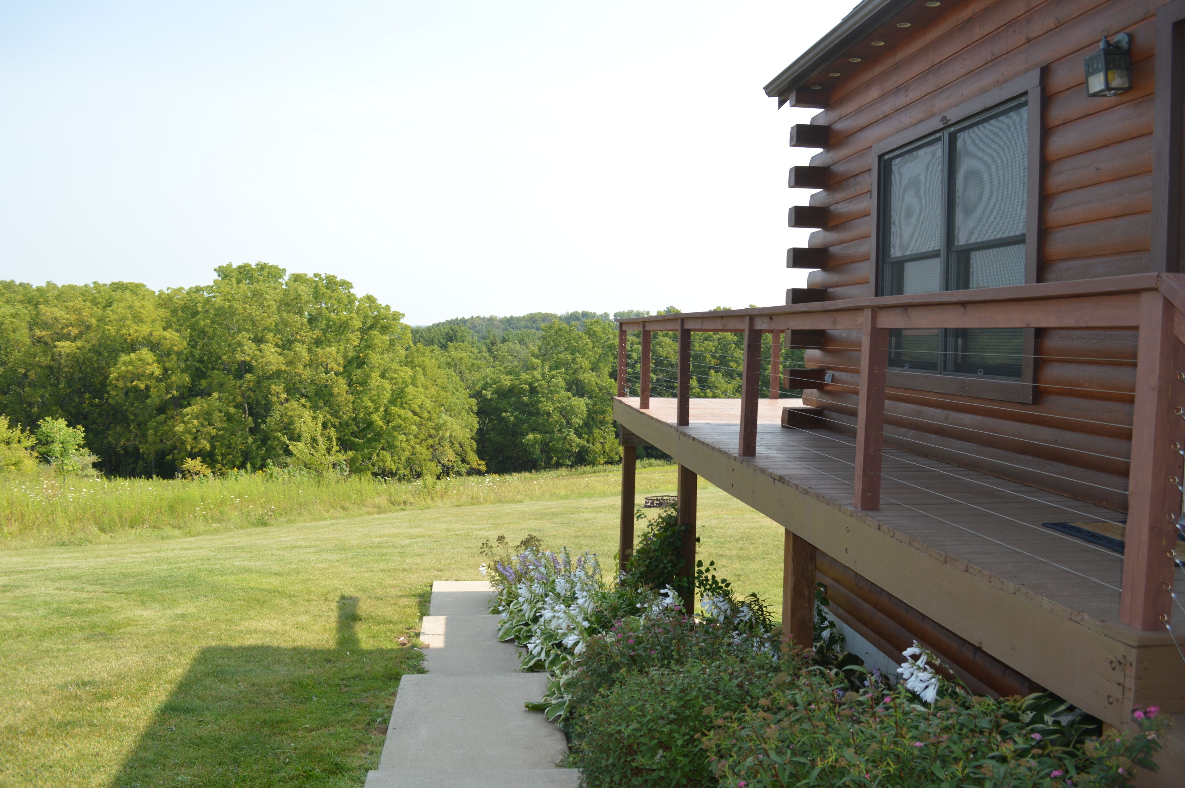 A wooden cabin with a deck and a view of a forested area.