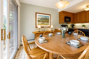 Un comedor con una mesa redonda de madera, sillas y vistas al exterior a través de un ventanal corredero.
