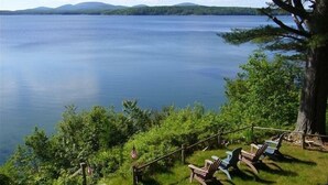 A lakeside view with a wooden deck and Adirondack chairs overlooking the water. - Acadia National Park-Oceanfront Cottage-Views of Cadillac Mountain & Acadia-Pets (Lamoine)