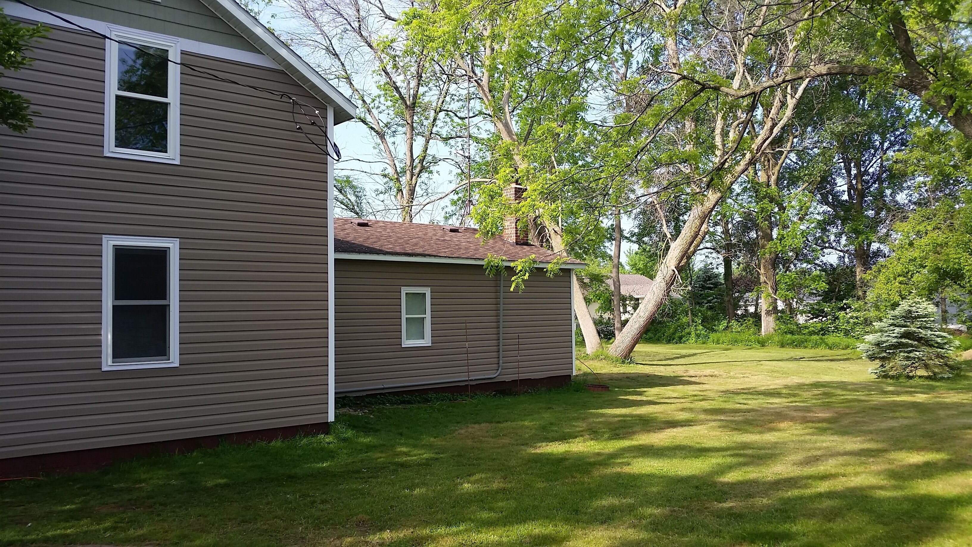 A two-story house with a brown siding exterior, a small front porch, and a well-maintained lawn.