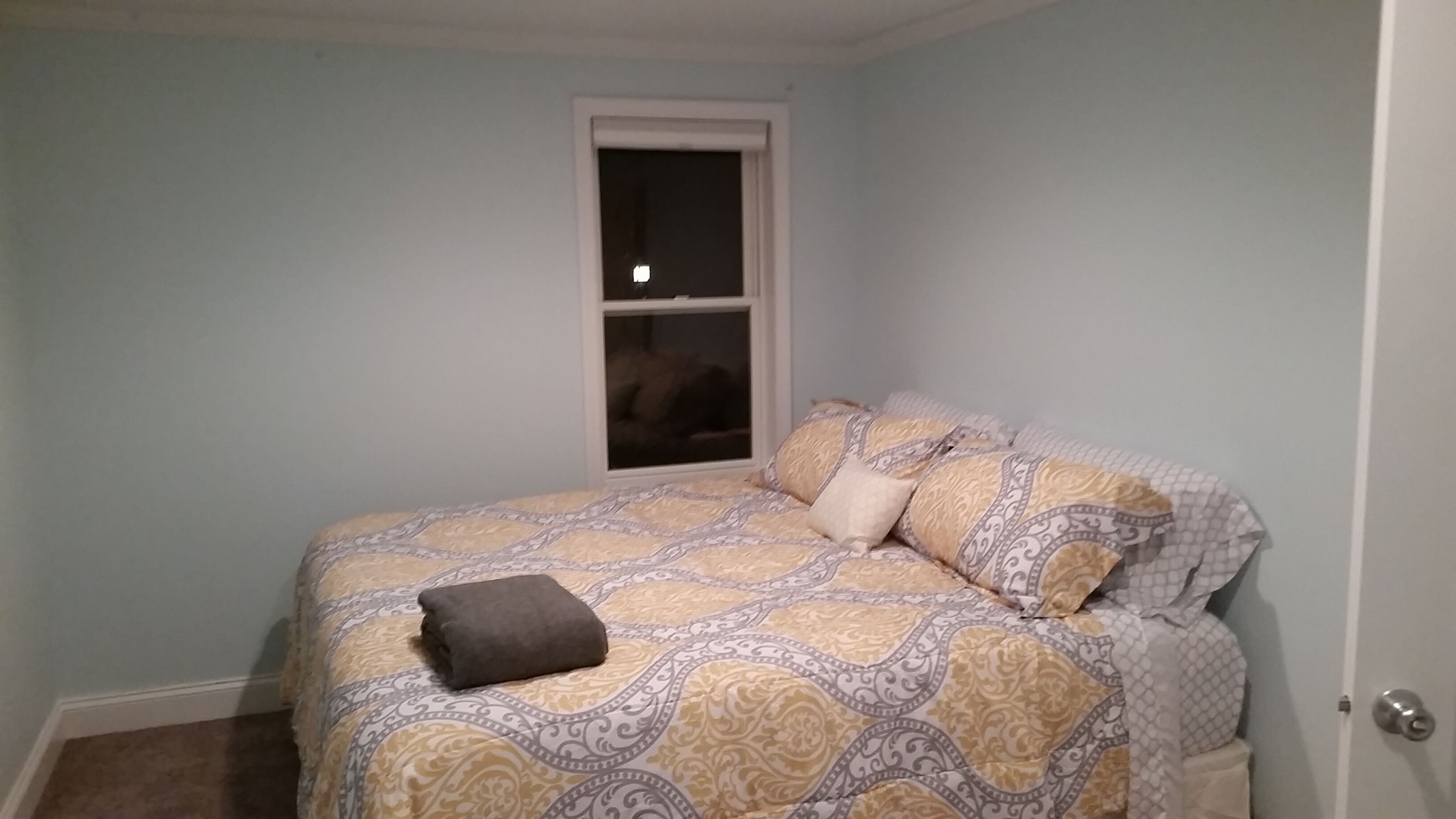 A bedroom with a bed, a window, and a door.