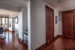 Un couloir avec un plancher en bois, un coin repas avec une table et des chaises, et une cuisine équipée d’une cuisinière.