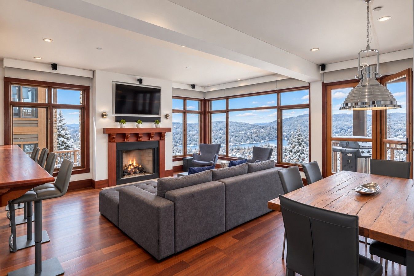 A modern living room with a fireplace, large windows, and a dining area.