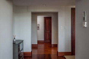 Un couloir doté d’un plancher en bois, d’une armoire de couleur sombre et d’une porte au fond.