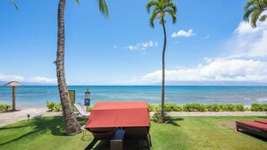 Un espace de détente aménagé sur la plage, avec un auvent rouge, une table de billard et une vue sur l’océan.
