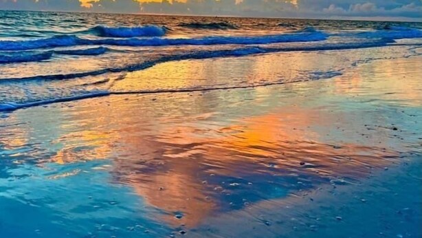 Ein Strand mit Wellen und einem Sonnenuntergang.