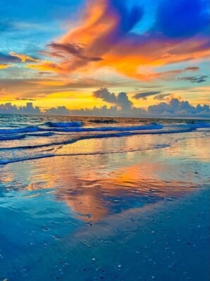 Una playa con olas y un atardecer.
