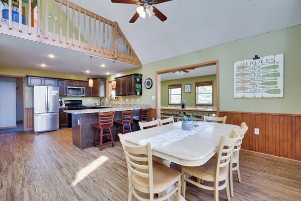 A spacious kitchen with a dining area, wooden flooring, and a ceiling fan.