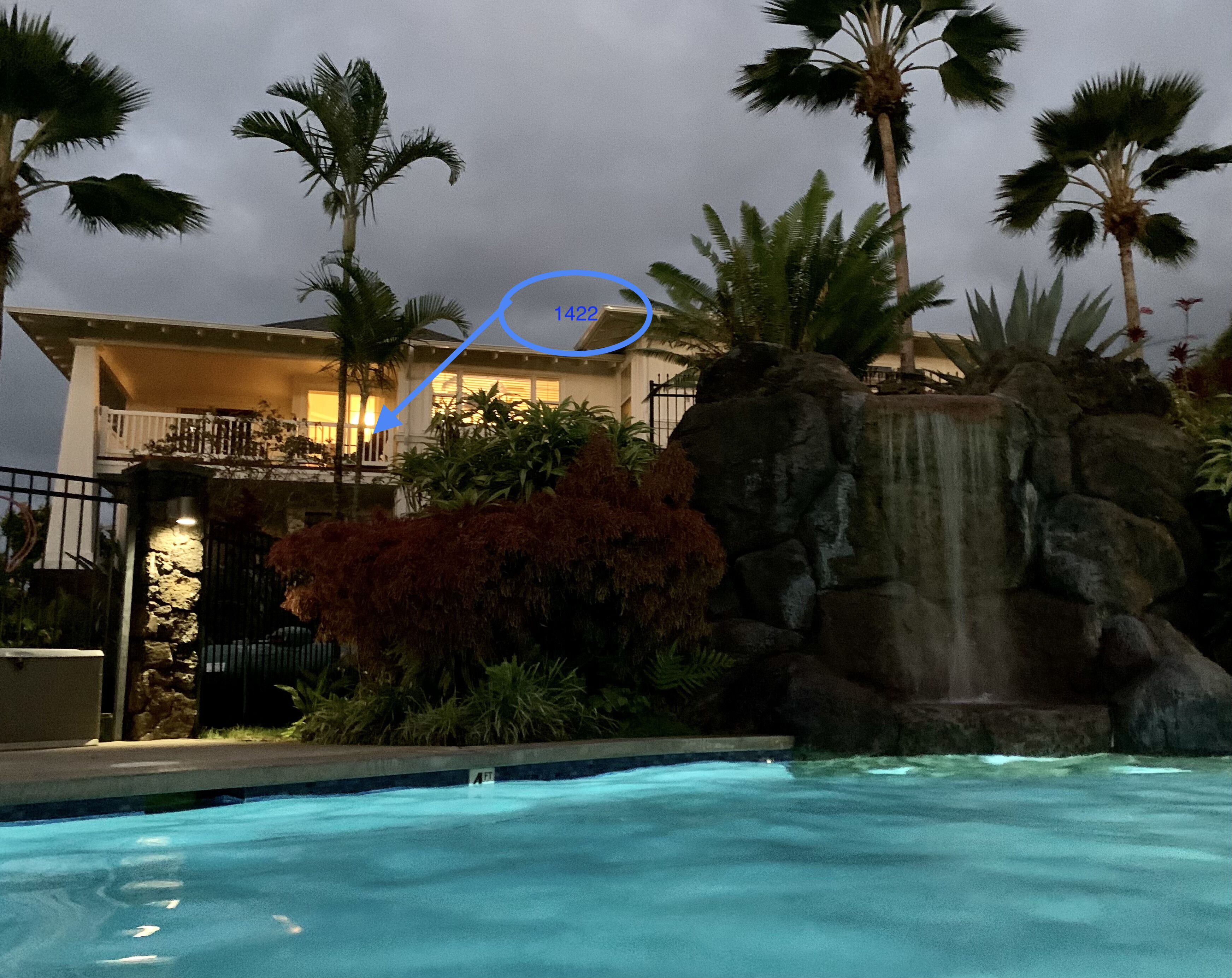Ein Pool mit Wasserfall, Palmen und ein Gebäude mit Balkon.