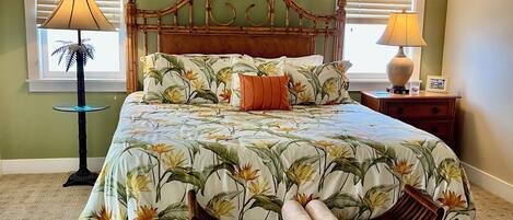 A bedroom with a bed, a ceiling fan, two bedside lamps, a nightstand, and a window with blinds.