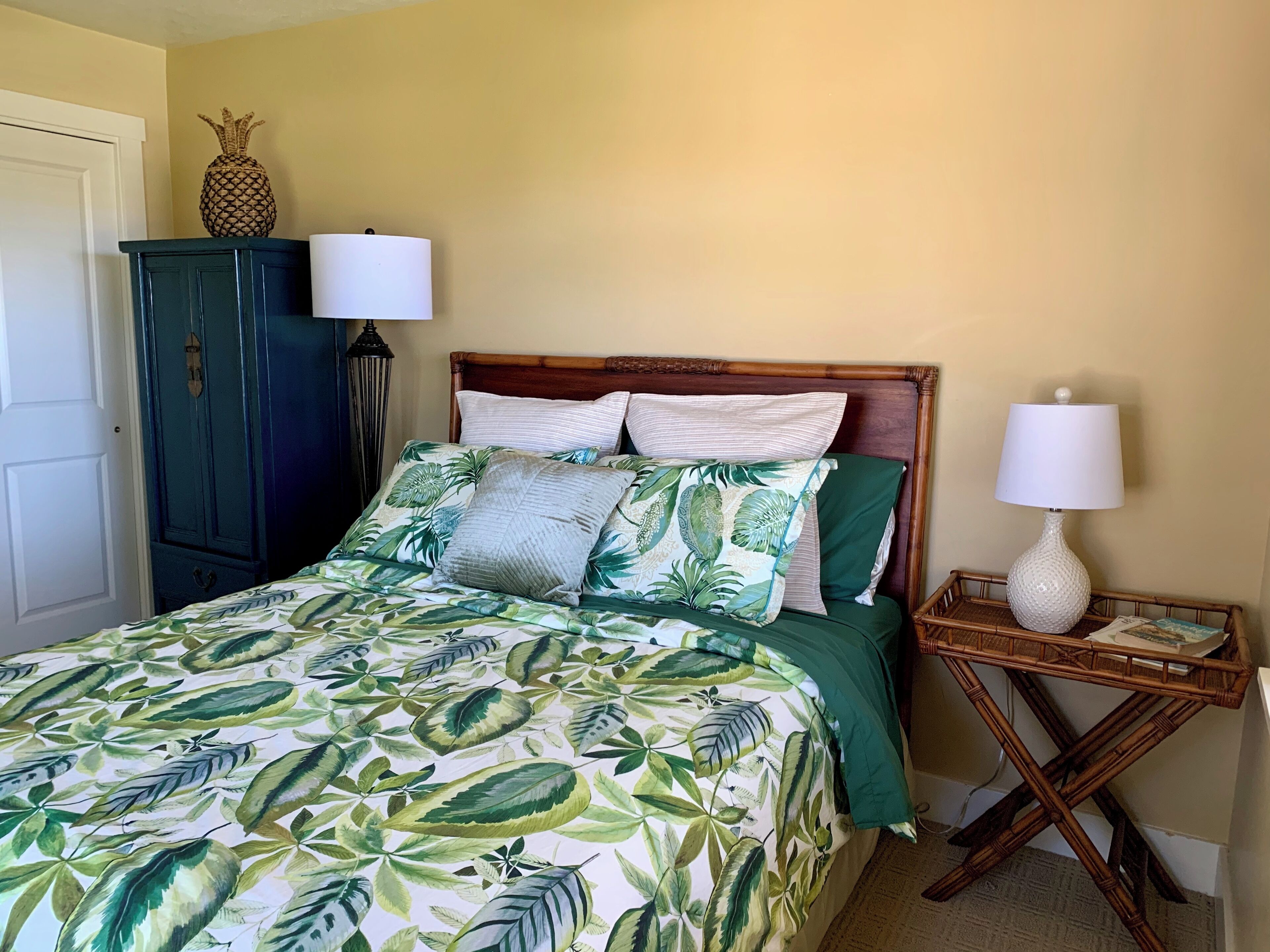 Un dormitorio con cama, mesita de noche, lámpara, armario y una piña decorativa.