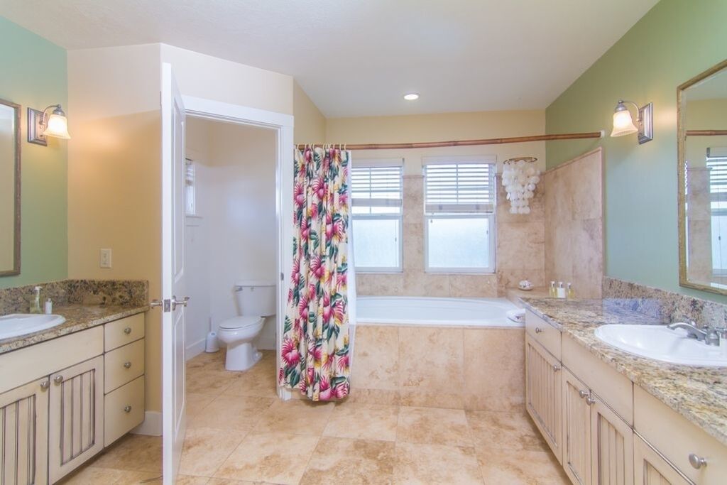 A bathroom with two sinks, a bathtub, and a toilet.