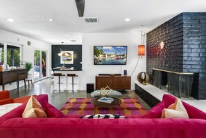 A modern living room with a red sofa, a glass coffee table, and a fireplace.