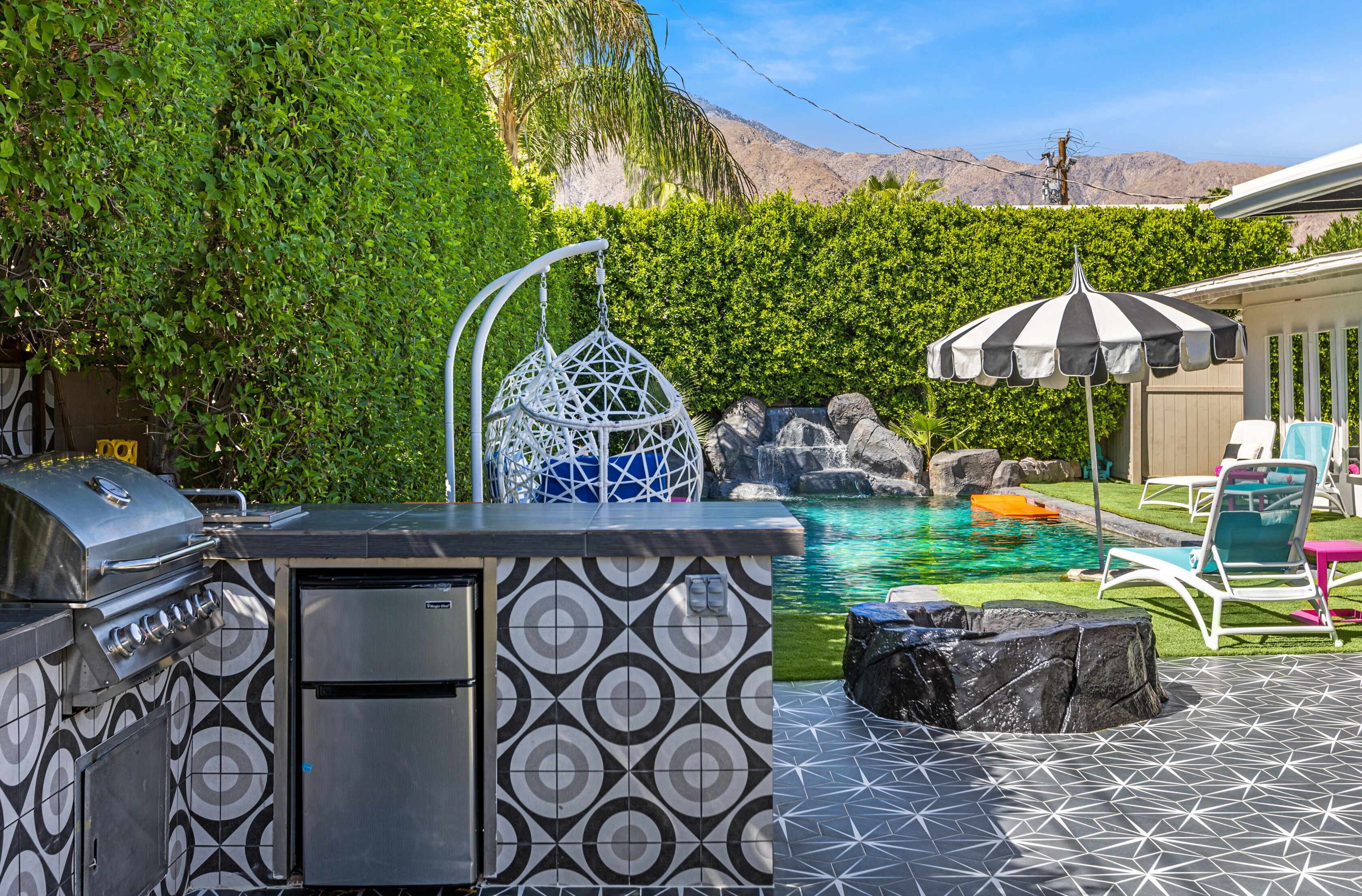 A backyard with a pool, a grill, and a hanging chair.
