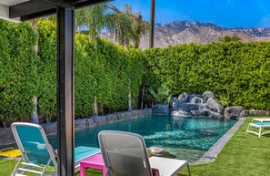 Ein Garten mit Swimmingpool, Wasserfall und Blick auf die Berge.