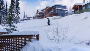 A ski resort with snow-covered slopes, wooden buildings, and a wooden fence.