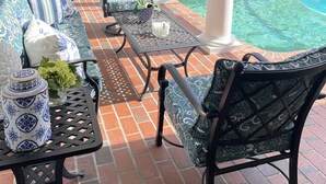 Un espacio al aire libre cubierto con piscina, asientos y una parrilla.