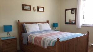 A wooden four-poster bed with a striped bedspread, two bedside tables with lamps, and a mirror on the wall. - Adorable One Bedroom One Bathroom With Easy Access To The Beach!  (Redington Beach)