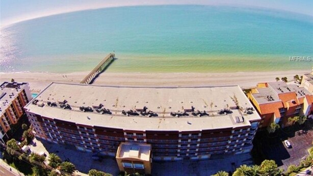 A large hotel with a curved roof, a parking lot, and a view of the ocean. - Adorable One Bedroom One Bathroom With Easy Access To The Beach!  (Redington Beach)