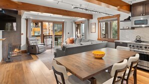 A modern kitchen with a large island, built-in oven, and a dining area with a wooden table and chairs.
