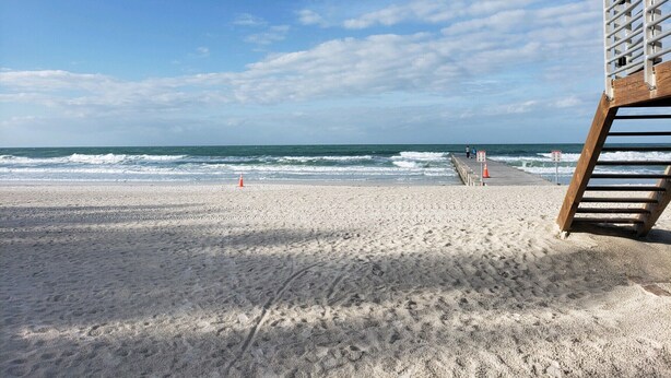 A beach with a lifeguard tower, a sandy shore, and the ocean in the background. - Coastal Bliss (Bradenton Beach)