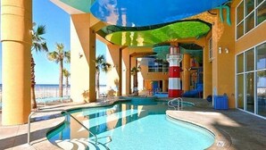 Un espace piscine à la forme circulaire, agrémenté de palmiers et offrant une vue sur l’océan.