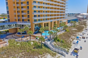 Un hotel de varios pisos con balcones, piscina y zona de playa.