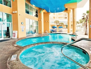 Zona de piscina con dos jacuzzis, un área de estar techada y un cartel que indica que la piscina está cerrada.