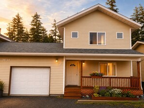 A two-story house with a garage, a front porch with a wooden railing, and a mailbox. - Puffin Perch 3 Bed 2.5 Bath House & Save 10% on Rental Car in 2026 (Kodiak)