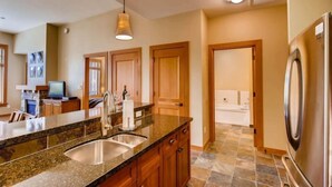 A modern kitchen with granite countertops, wooden cabinets, a stainless steel refrigerator, and a built-in dishwasher. - Capitol Peak Lodge 3123 (Snowmass Village)