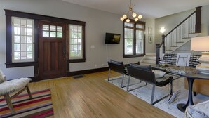 A spacious living room with a dining area, wooden flooring, a chandelier, and a staircase. - Classic 12 South Bungalow (Nashville)