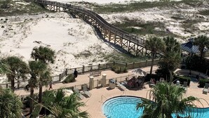 Un resort frente al mar con un paseo marítimo de madera, una zona de piscina y sombrillas de playa.