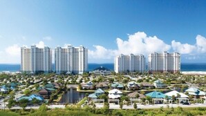 Un resort costero con edificios altos, un puerto deportivo y una vista despejada del océano.
