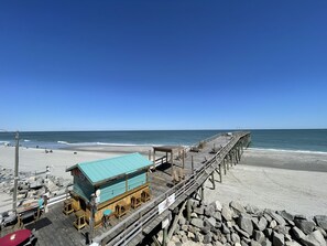 A beachside wooden pier with a restaurant and seating area.