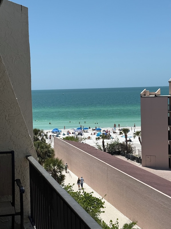A balcony overlooking a beach with a clear view of the ocean and a sandy shore.