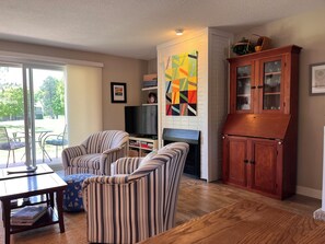A living room with striped sofas, a TV, a fireplace, a cabinet, and a view of the outdoors.