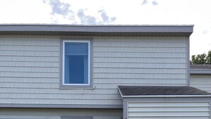 A two-story building with a front entrance, two windows, and a small utility shed. - Cozy and Convenient! (Cedar)