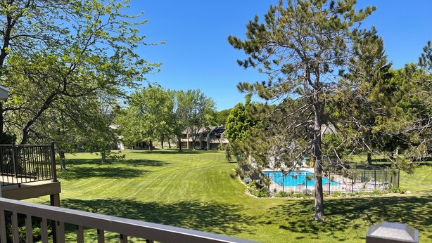 A residential backyard with a swimming pool, a wooden deck, and a well-maintained lawn. - Cozy and Convenient! (Cedar)