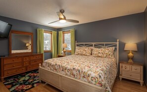 Un dormitorio con cama, cómoda, mesita de noche y ventilador de techo.
