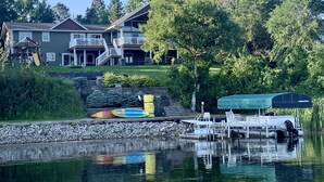 Una casa de dos pisos con un muelle y un bote.