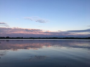Un lago tranquilo con un barco a lo lejos y un cielo despejado.