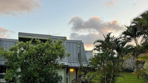 A modern building with a green facade, surrounded by lush greenery and a well-maintained lawn. - Beautiful 2/2 Townhouse in Princeville, Free WiFi, Cable TV, BBQ, beach gear (Princeville)