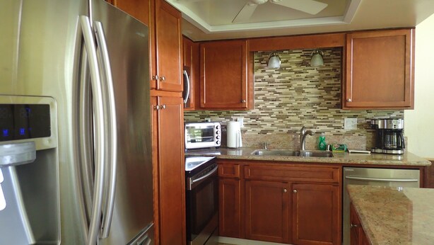 A kitchen with wooden cabinets, stainless steel appliances, a microwave, a toaster, and a coffee maker. - Beautiful 2/2 Townhouse in Princeville, Free WiFi, Cable TV, BBQ, beach gear (Princeville)