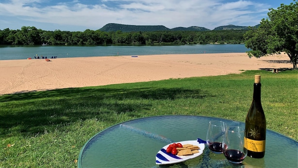 A glass table with a bottle of wine, glasses, and a plate of snacks by a lakeside view. - Million-dollar View & Affordable Too! Kayaks free for use (Kingsland)