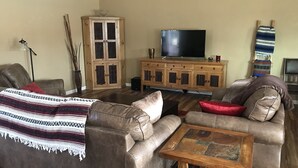 Un salon avec un canapé marron, une table basse en bois et un téléviseur posé sur un meuble en bois.