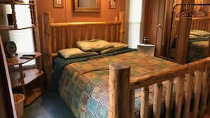 A cozy bedroom with a wooden headboard, a bed with a patterned quilt, a nightstand, a wooden dresser, and a mirror. - Vacation Rental in Westfield/Oxford, Wis., with acres of nature … (Oxford)