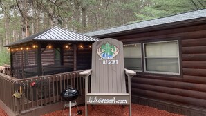 A wooden cabin with a deck, a covered seating area, and a sign for Lilikois Resort. - Vacation Rental in Westfield/Oxford, Wis., with acres of nature … (Oxford)
