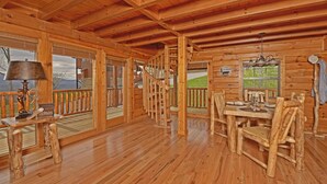 Ein Interieur einer Holzhütte mit Essbereich, einer Treppe und großen Fenstern.