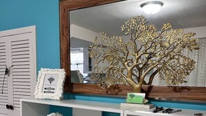A white console table with shelves, a decorative tree, and a mirror. - Shabby Chic Duplex Tx Medical Center, Rice Village (Houston)