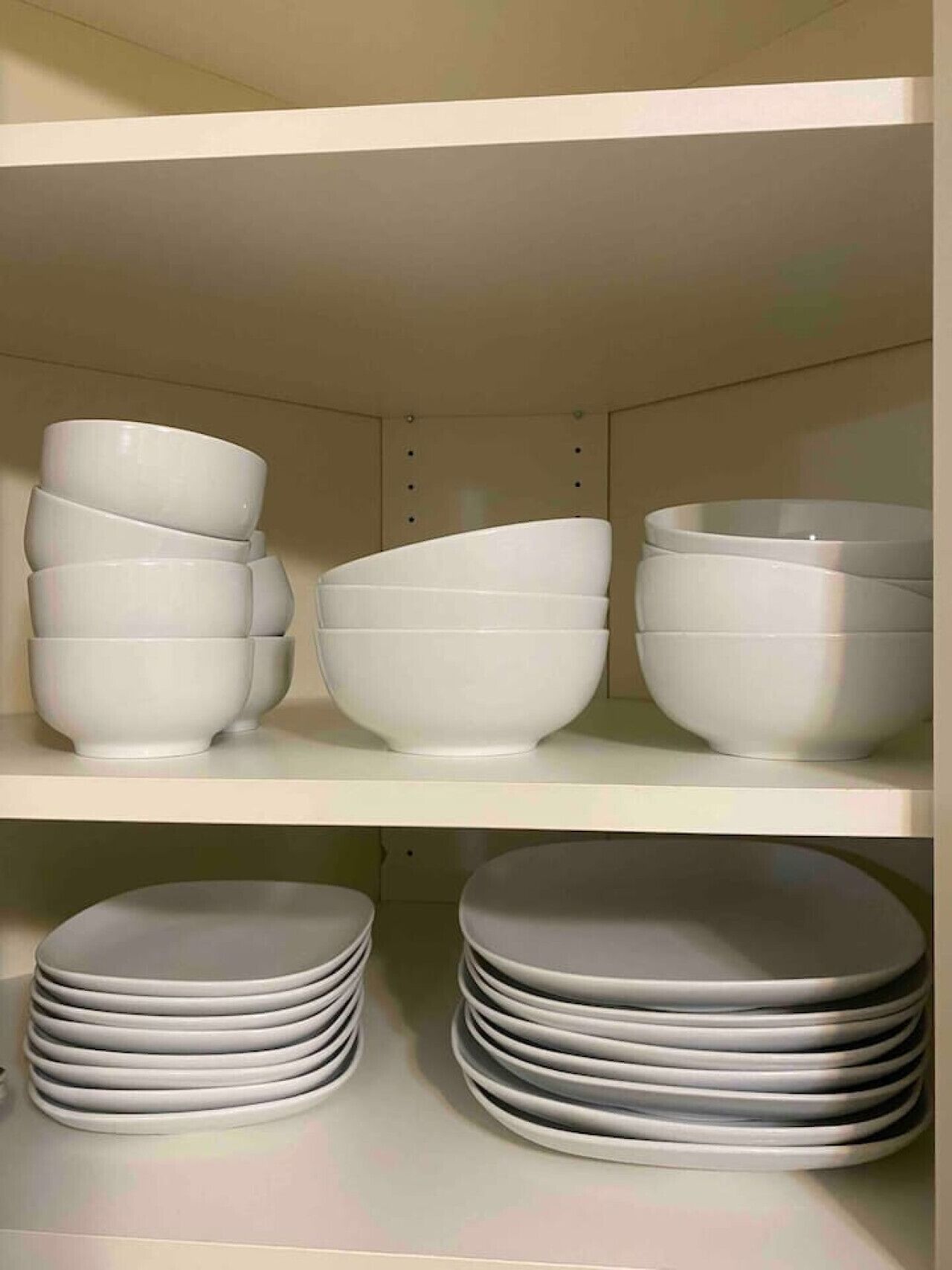 A shelf with white bowls and plates.